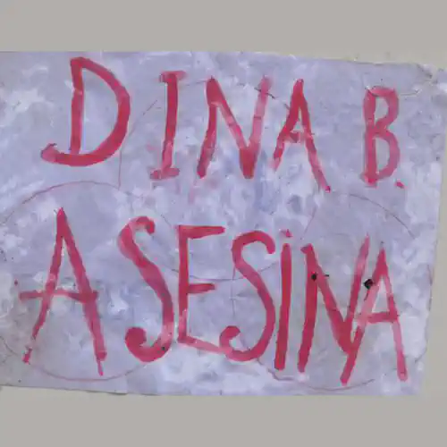 Cartel escrito con tinta roja representando sangre que dice: Dina Asesina.